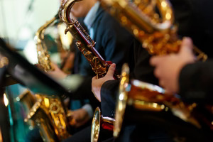 A close-up of several saxophones with the players' hands only available